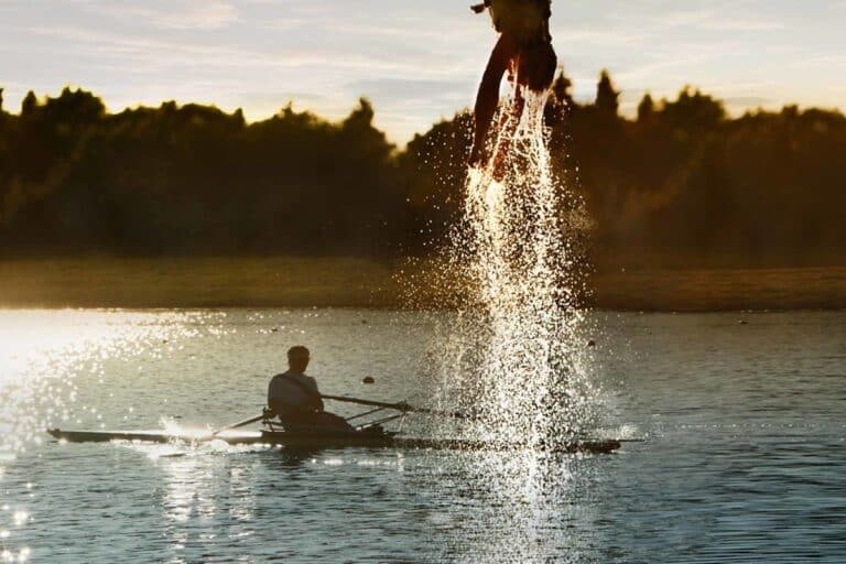 Person kommt mit nassem Kopf aus dem Wasser ausgetaucht nach Dip-In beim Bungee Jumping in München an der Regattaanlage