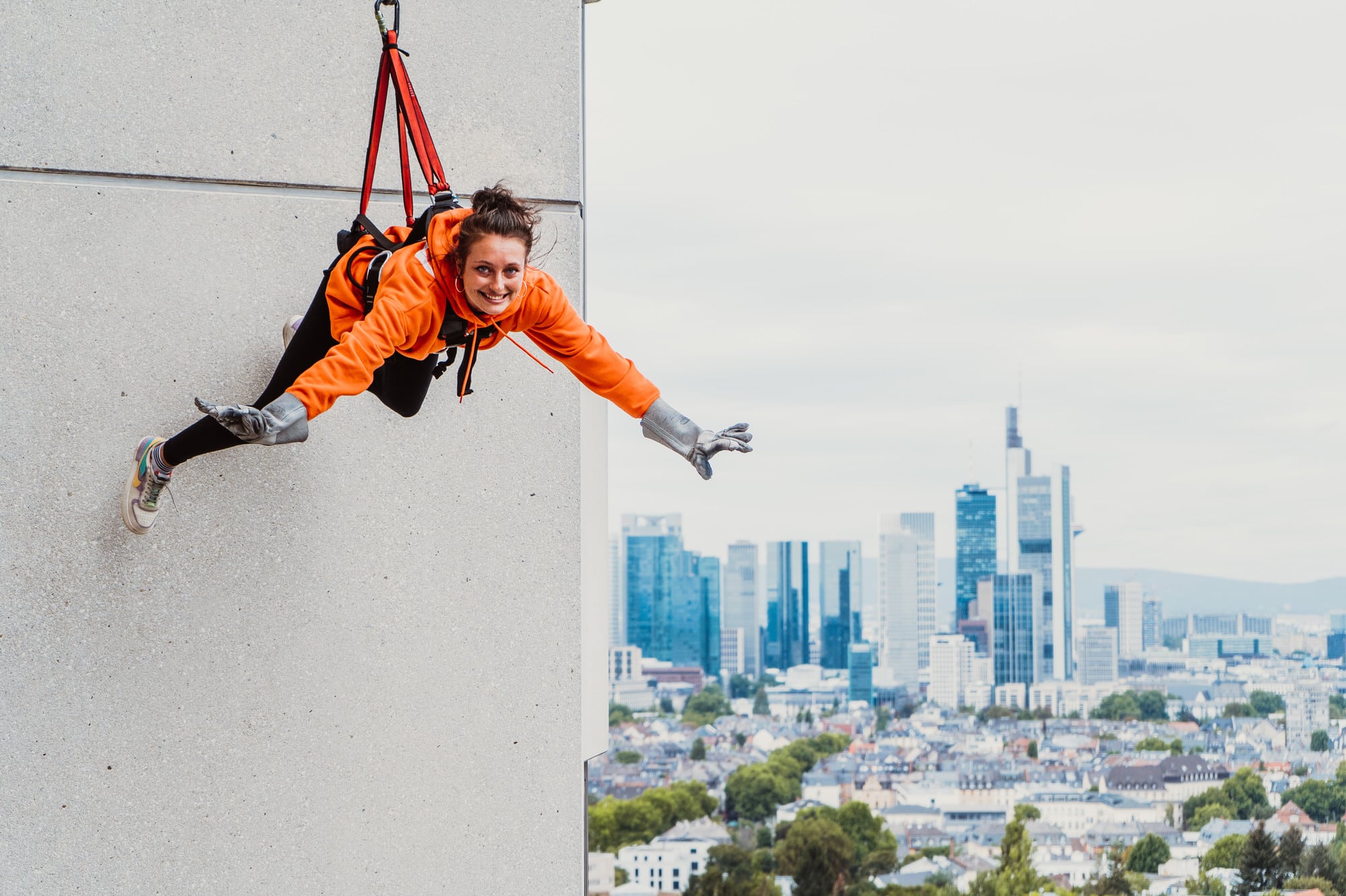 Frau hängt in der Höhe beim House Running neben Skyline Frankfurts