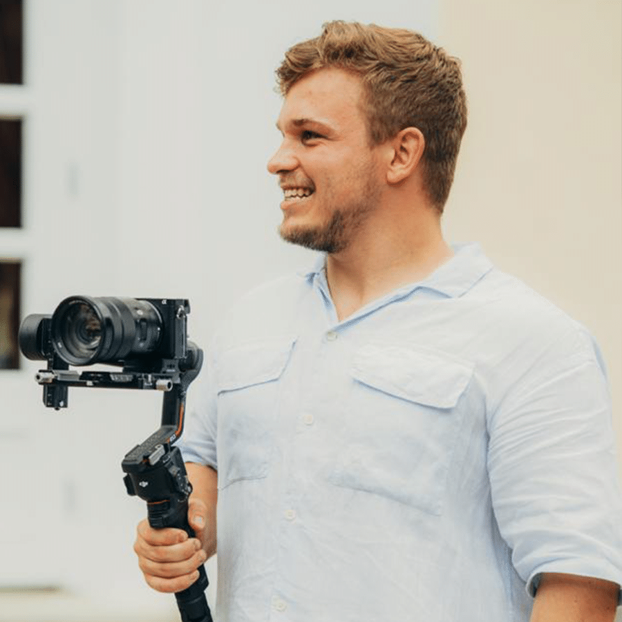 Person mit Kamera in der Hand lächelt zur Seite.